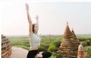 Woman practicing yoga near ancient temples.