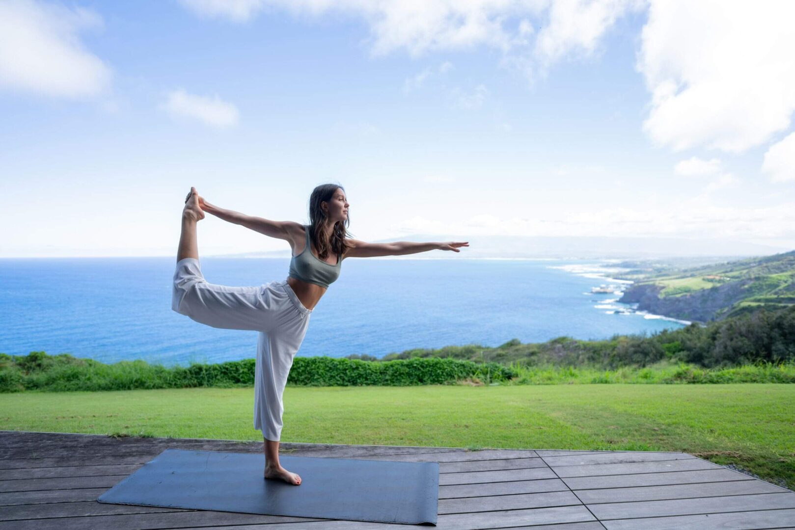 Woman practicing yoga outdoors by ocean.